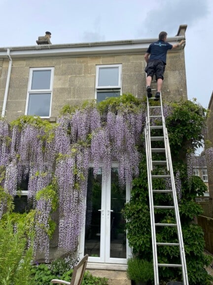 Professional gutter cleaning service in Bath, clearing leaves and debris from a residential gutter